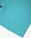 Closer view bottom-right section of aqua-blue, buttoned organic cotton overshirt from Uskees. Focus on hem, hip pocket and corozo buttons.