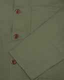 Close-up of a men's green Uskees shirt jacket sleeve and brown buttons 