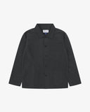 Front flat shot of black, buttoned ripstop overshirt. Clear view of chest and hip pockets, corozo buttons and Uskees branding label.