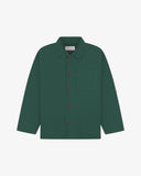 Front flat shot of green, buttoned organic cotton overshirt. Clear view of chest and hip pockets, corozo buttons and Uskees branding label.