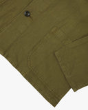 Close-up view of an Uskees shacket in  green linen blend showing a button, pocket and cuff detail on a white background.