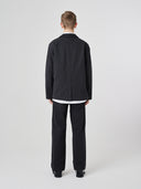 Back view of male model wearing the Uskees 3047 Docklands black blazer unbuttoned with view of back vent.