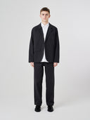 Front view of male model wearing the Uskees 3047 Docklands black blazer unbuttoned, paired with matching Uskees pants.