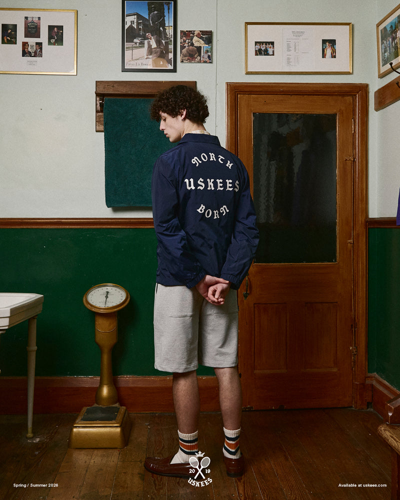 Back view of a man wearing a navy blue Uskees jacket with focus on the the North Born Uskees slogan.