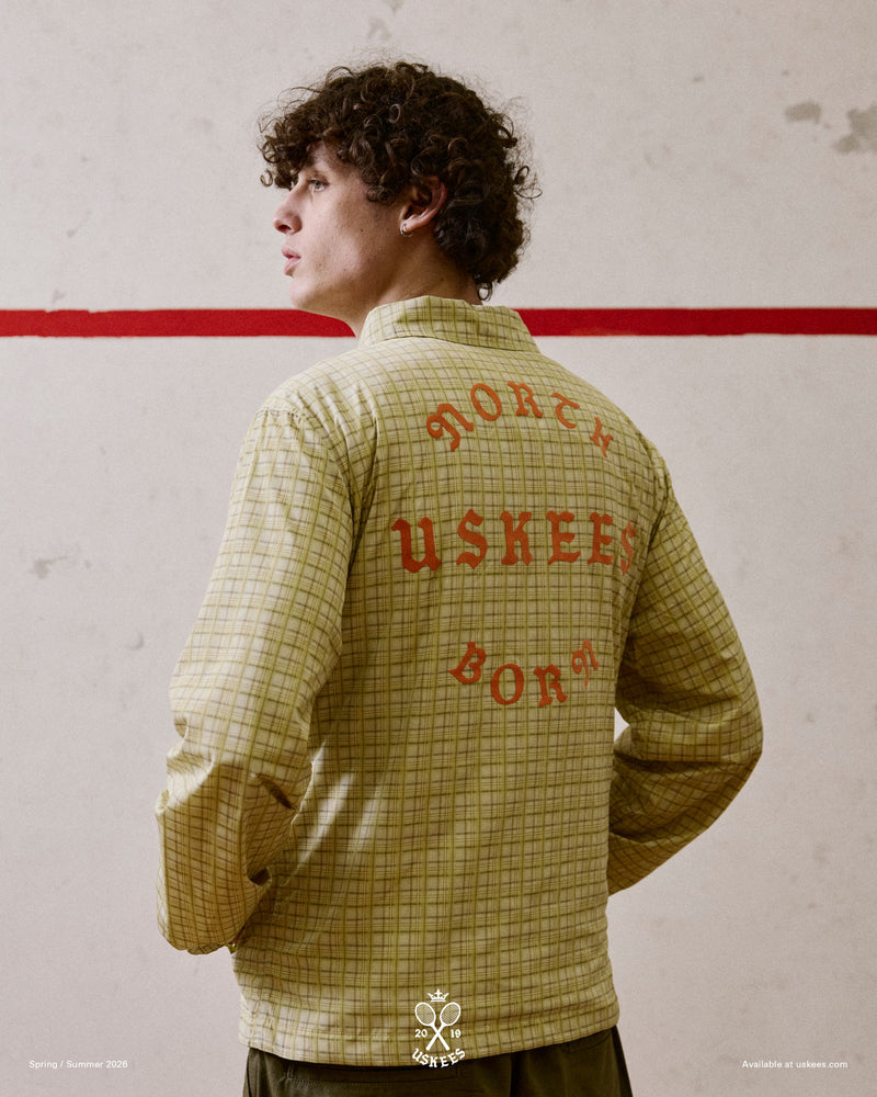 Back view of a man wearing a yellow checkered Uskees jacket with focus on the the North Born Uskees slogan.
