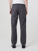 Close-up back view of model wearing Uskees twill workwear pants in charcoal-grey showing the buttoned back pocket and waist adjuster buttons.
