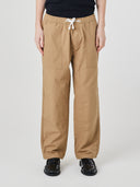 Front view of model wearing  5020 ripstop utility pants in khaki. Indicating drawstring, tapered fit on the leg, deep front pockets and reinforced knee patches. 