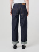 Bottom-half back view of male model wearing Uskees raw orta denim workwear pants in dark indigo, with focus on two back patch pockets.