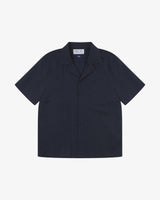 Front flat shot of Uskees dark blue Cuban short sleeve shirt for men. Clear view of corozo buttons, chest pocket and Uskees branding label.