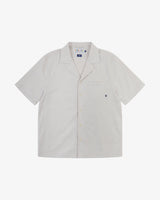 Front flat shot of Uskees off-white Cuban shirt for men. Clear view of corozo buttons, chest pocket and Uskees branding label.
