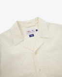 Frontclose up shot of Uskees cream linen blend short-sleeve Cuban shirt for men showing the brand label.