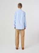 Reverse view wearing Uskees light blue men's Oxford shirt, paired with Uskees khaki pants.