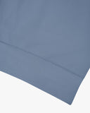 Closer view view of the discreet brand logo on ribbed hem of the Uskees cornflower blue organic heavyweight cotton 7005 jersey sweatshirt.