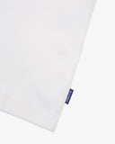 View of hemline of Uskees white cotton vest with focus on breathable, non-see-through fabric and blue 'USKEES' logo tab.