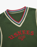 Front close view of a green sleeveless sweater vest with 'USKEES' branding on the front in red.