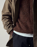 Close shot of a male model wearing an Uskees brown shacket, loam brown sweater, and dark blue trousers.