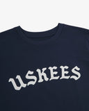 Neckline close-up of navy blue organic cotton T-shirt, with focus on the neck tape reinforcement and B-Boy inspired brand graphics in white.