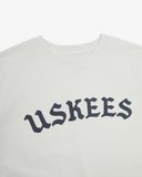Neckline close-up of white organic cotton T-shirt, with focus on the neck tape reinforcement and B-Boy inspired brand graphics in navy blue.